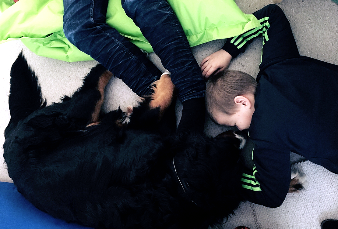Poika makaa lattialla Nella-koiran kanssa.