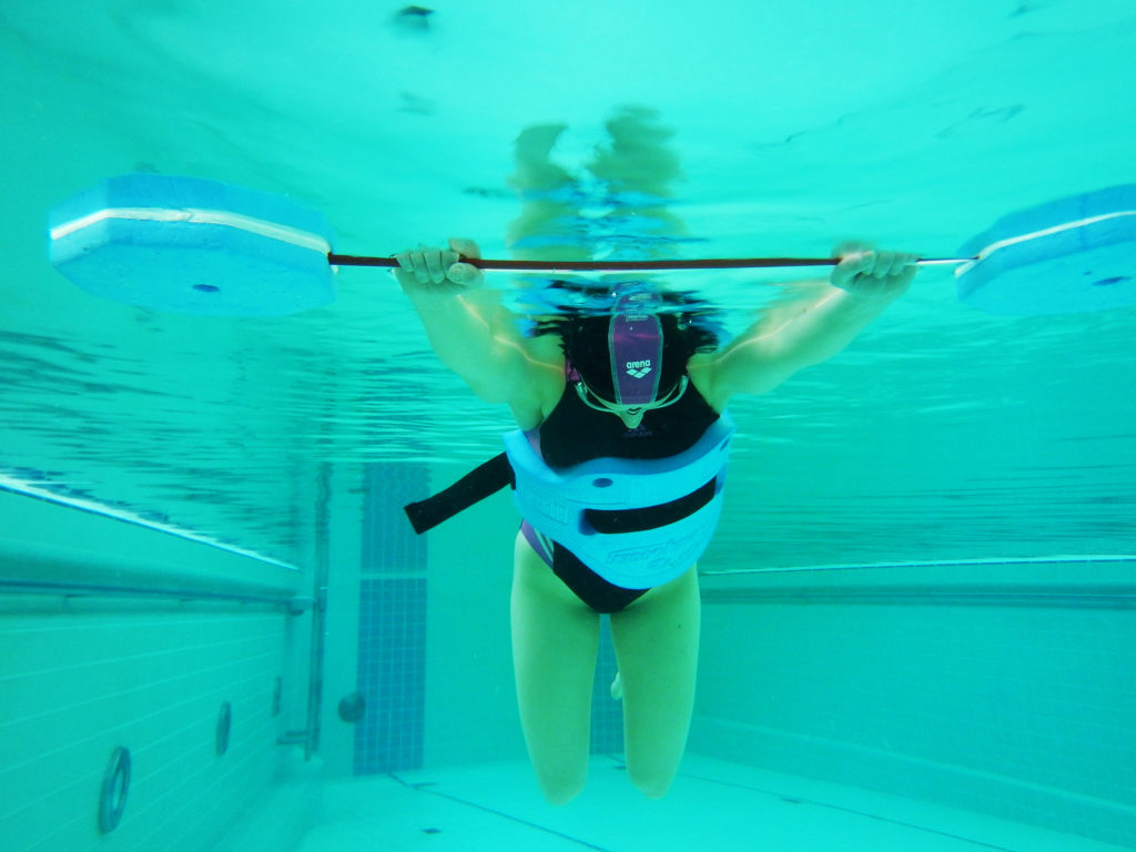 Kuvassa uimari harjoittelee kasvot vedessä kellumista uimaseipään ja vesijuoksuvyön avulla.