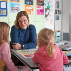 Oppimis- ja ohjauskeskus Valterin konsultoiva ohjaaja Henni Huttunen istuu pöydän ääressä kahden lapsen kanssa. Pöydällä on KESY-kuvakortteja levitettynä.